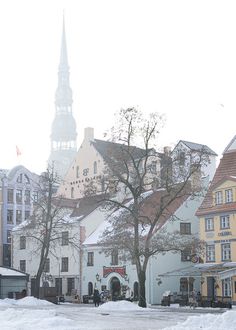 people walking in the snow near some buildings