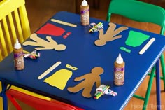 children's play table with construction paper cutouts and glue on it, including two plastic chairs