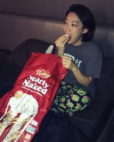 a woman sitting on a bed brushing her teeth with a bag in front of her