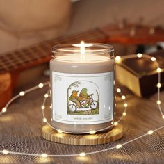 a lit candle sitting on top of a wooden table next to a string of lights