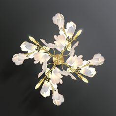 a chandelier with white flowers hanging from it's center and gold accents