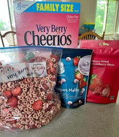 bags of cereal are sitting on the counter next to some bagged strawberries and yogurt mix