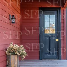 a blue door on the side of a red house with flowers in a wooden planter