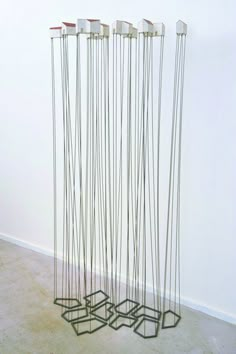 four metal sculptures are standing in the middle of a room with white walls and concrete flooring