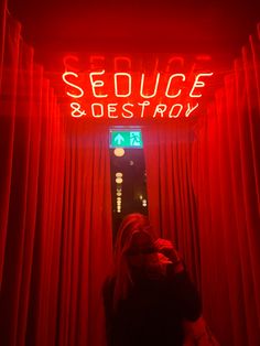 a woman standing in front of a red neon sign