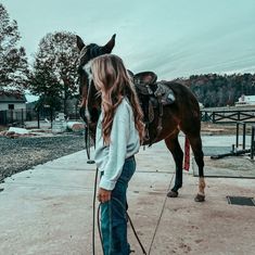 a girl standing next to a brown horse