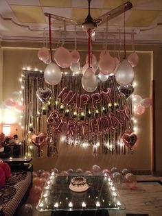 a room with balloons, lights and a cake on the table in front of it