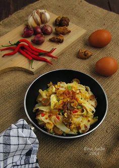 a bowl filled with food sitting on top of a table next to eggs and vegetables