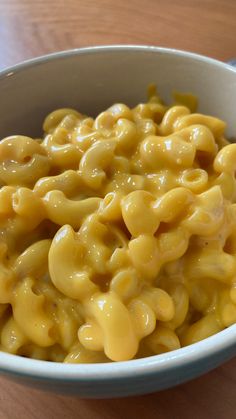 a white bowl filled with macaroni and cheese on top of a wooden table