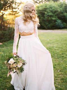 a woman in a white dress holding a bouquet and wearing a long sleeved top