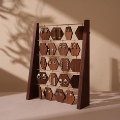 a wooden display case with earrings and necklaces on it's sides, in front of a wall