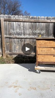 a wooden dresser sitting on top of a cement floor next to a fence with words written on it