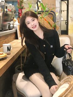 a woman sitting on top of a white chair next to a table with a bag