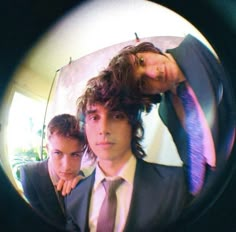 two young men in suits and ties looking through a magnifying glass with one man holding his head