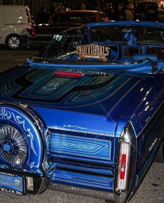 a blue car parked on the side of the road with its hood up in front of it