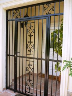 an iron gate is open in front of a door on the side of a house