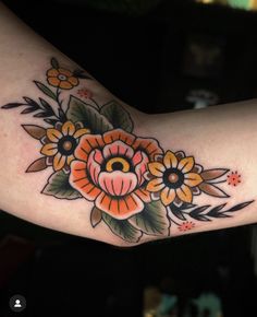 a woman's arm with an orange flower and leaves tattoo design on the arm