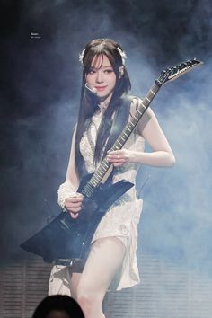 a woman in white dress playing an electric guitar