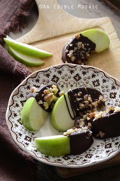 an apple slice with nuts and chocolate on a plate next to two green pears