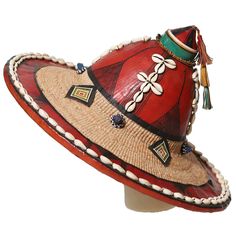 Our Fulani hat is made out of an organic plant fiber with leather applications and Cowrie shells. At the base of the hat there is a chinstrap with a tassel at the end. Handmade by Fulani artisans in Mali. No two are the same due to the nature of handmade. This is also a great wall decor! One size fits all. Traditional Toquilla Straw Hat With Curved Brim, Traditional Brown Straw Hat With Curved Brim, Traditional Brimmed Panama Hat For Festival, Traditional Palm Leaf Hat With Curved Brim, Traditional Handwoven Fedora Hat, Traditional Handmade Brown Straw Hat, Handmade Palm Leaf Hat For Festivals, Handmade Palm Leaf Hats For Festivals, Handmade Artisan Wide Brim Mini Hats