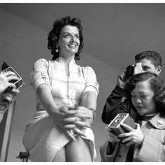 an old photo of a woman sitting in front of two men and taking pictures with their cell phones