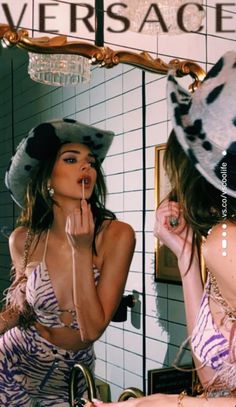 a woman is brushing her teeth in front of a mirror and wearing a zebra print bathing suit