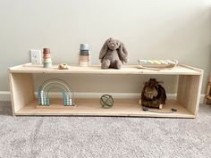 a stuffed animal sitting on top of a wooden shelf next to other toys and items