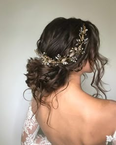 the back of a woman's head wearing a bridal hair comb with gold leaves on it