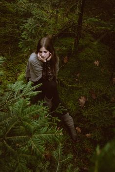 a woman standing in the woods talking on her cell phone