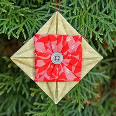 an ornament hanging from a christmas tree decorated with red and white fabric, has a button in the center