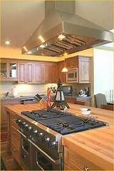 a stove top oven sitting inside of a kitchen next to wooden counter tops and cabinets