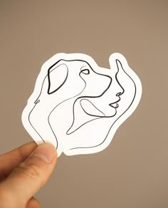 a hand holding up a sticker with a dog's face drawn on it