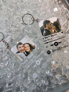 a couple's keychain is laying on some ice and has two photos attached to it