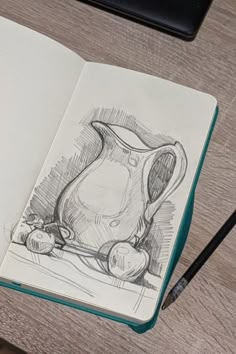 an open notebook with a drawing of a pitcher and apples on the table next to it