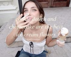 a woman sitting on the ground holding an ice cream cone in front of her face