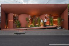 a building that has plants growing on it's side and people walking by the entrance