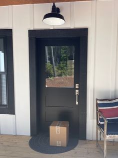 a cardboard box sitting in front of a black door with a window on the side