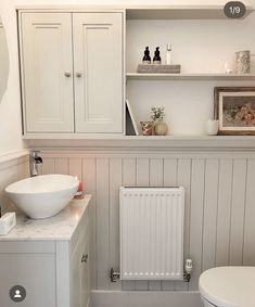 a bathroom with white walls and flooring has a radiator next to the toilet