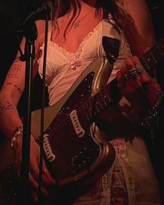 a woman holding a guitar in front of a microphone