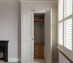 an empty room with white cupboards and a fire place in the corner next to it