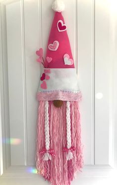 a pink and white gnome hat hanging on the side of a door with hearts painted on it