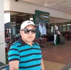 a man wearing sunglasses and a hat standing in front of a store