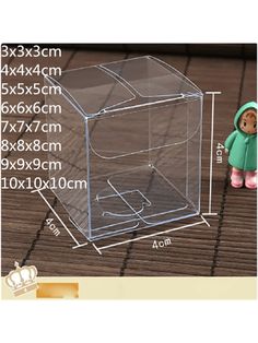 a clear plastic box with a small doll next to it on a wooden floor and measurements