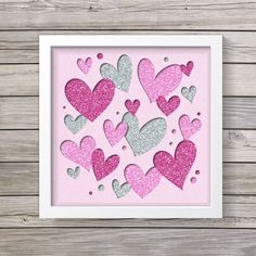 pink and silver glitter hearts in a white frame on a wooden surface with wood planks