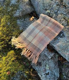 a blanket laying on top of a rock covered in moss