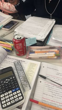 a table topped with lots of books and notebooks next to a calculator