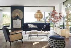 a living room with blue couches and chairs in front of large windows that look out onto the backyard