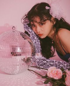 a woman leaning over a disco ball with her hand on the ground next to it