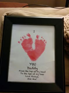 a hand and foot print in a black frame on a couch next to a teddy bear