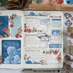 an open planner book with flowers and clouds on the pages, surrounded by other items